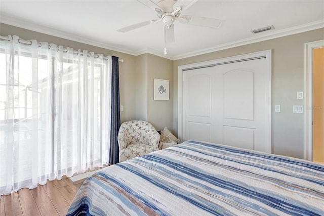 bedroom featuring wood-type flooring, ornamental molding, ceiling fan, and a closet