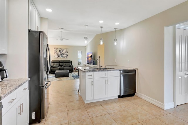 kitchen with white cabinetry, sink, light stone countertops, and stainless steel refrigerator