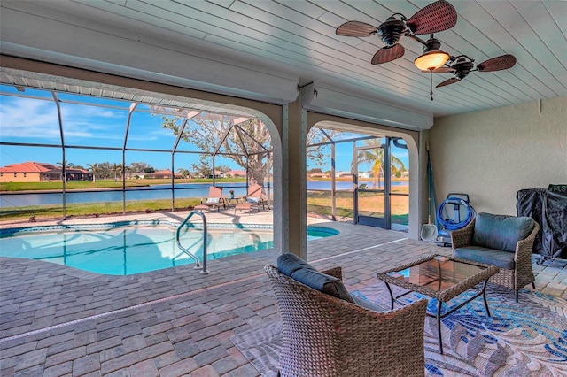 view of swimming pool with a water view, ceiling fan, a patio area, and glass enclosure