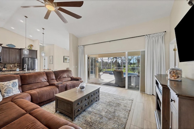 living room with ceiling fan, high vaulted ceiling, and light hardwood / wood-style flooring