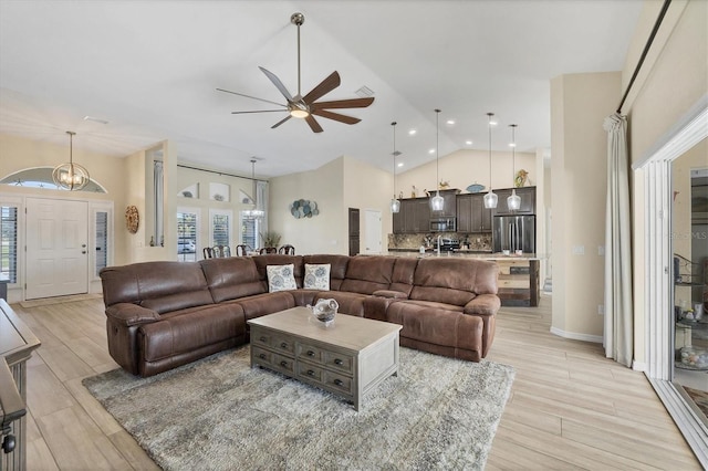 living room with ceiling fan with notable chandelier and high vaulted ceiling