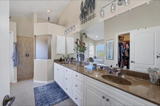 bathroom with vanity, vaulted ceiling, walk in shower, and tile patterned floors