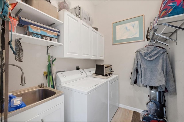 laundry room featuring washer and dryer, cabinets, light hardwood / wood-style flooring, and sink