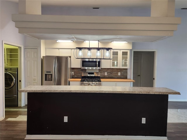 kitchen with stainless steel appliances, washer / clothes dryer, decorative light fixtures, decorative backsplash, and white cabinets