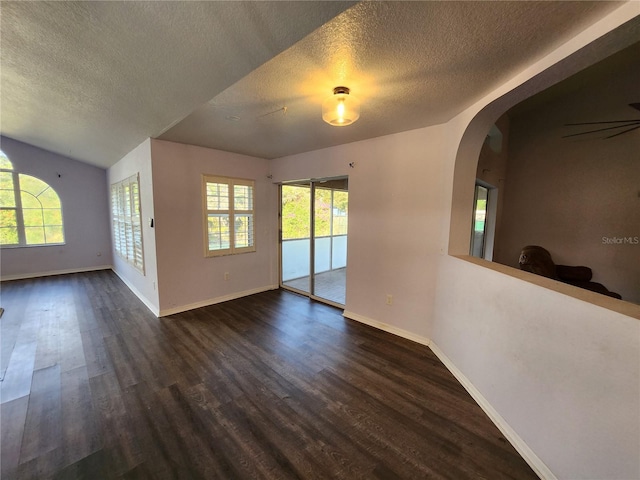 spare room featuring plenty of natural light, dark wood-type flooring, and a textured ceiling