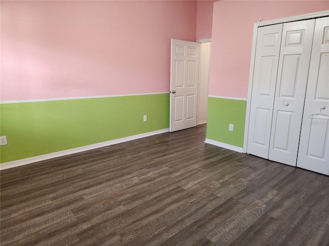 unfurnished bedroom featuring a closet and dark wood-type flooring