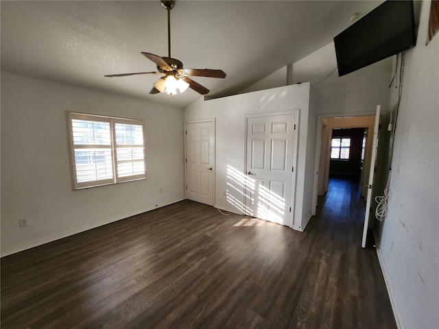 interior space with a textured ceiling, ceiling fan, dark hardwood / wood-style flooring, and lofted ceiling