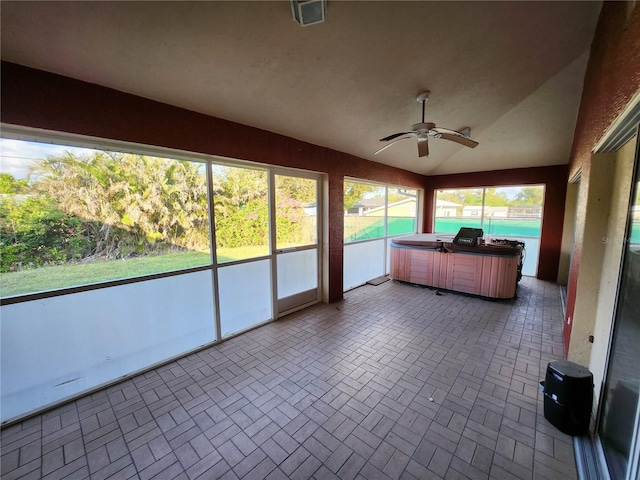 unfurnished sunroom featuring lofted ceiling, ceiling fan, and a hot tub