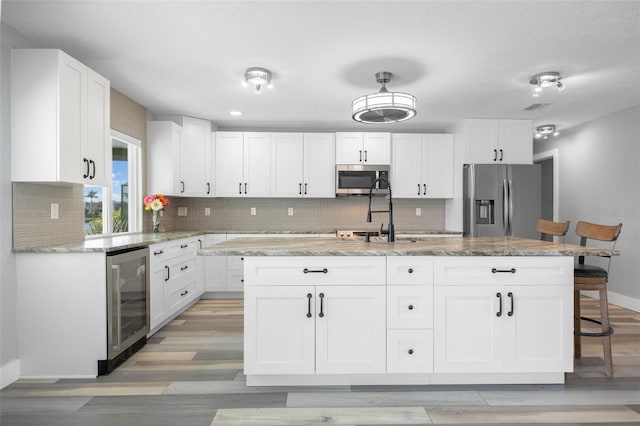 525 Madrid Blvd, Punta Gorda, FL 33950 - kitchen featuring wine cooler, stainless steel appliances, white cabinetry, and decorative backsplash