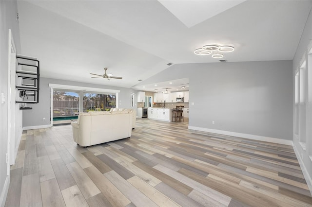 unfurnished living room featuring ceiling fan, light hardwood / wood-style flooring, and vaulted ceiling