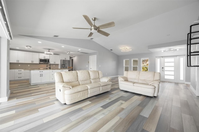 living room featuring ceiling fan, sink, light hardwood / wood-style flooring, and vaulted ceiling