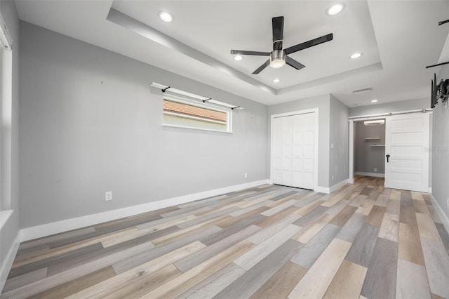525 Madrid Blvd, Punta Gorda, FL 33950 - unfurnished bedroom featuring a barn door, a raised ceiling, recessed lighting, light wood-style floors, and ceiling fan