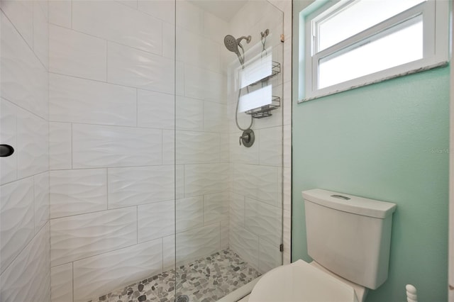 bathroom with a tile shower and toilet