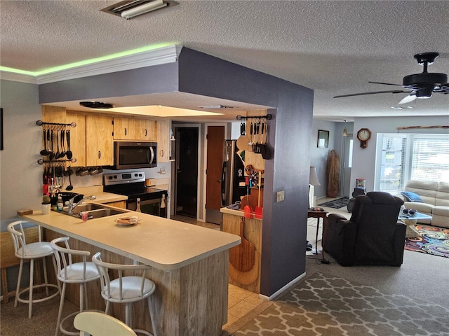 kitchen with a breakfast bar, sink, ceiling fan, appliances with stainless steel finishes, and kitchen peninsula