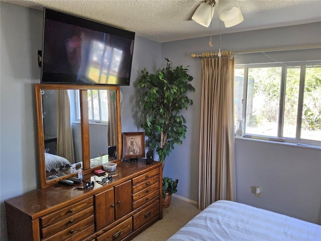 carpeted bedroom featuring ceiling fan and a textured ceiling