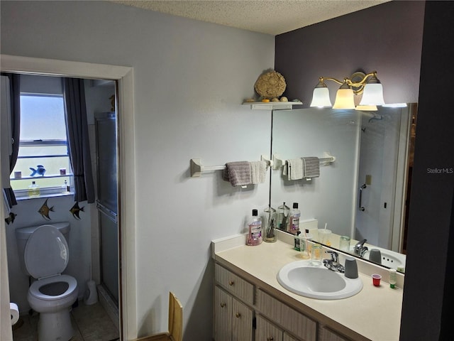 bathroom featuring vanity, toilet, an enclosed shower, and a textured ceiling