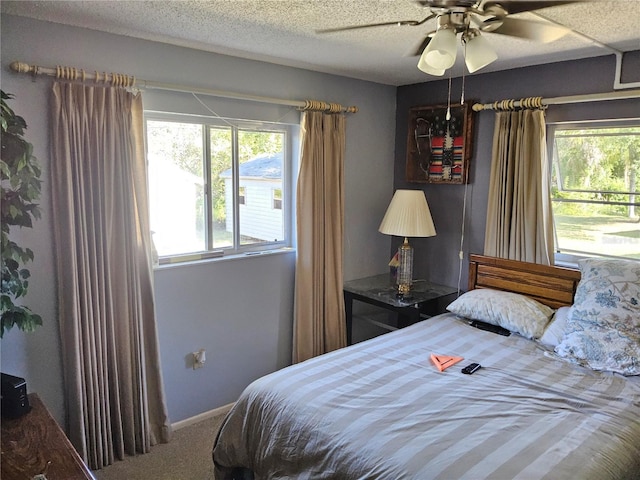 bedroom with ceiling fan, carpet floors, and a textured ceiling