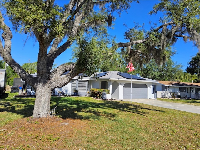 ranch-style home with solar panels, a garage, and a front lawn