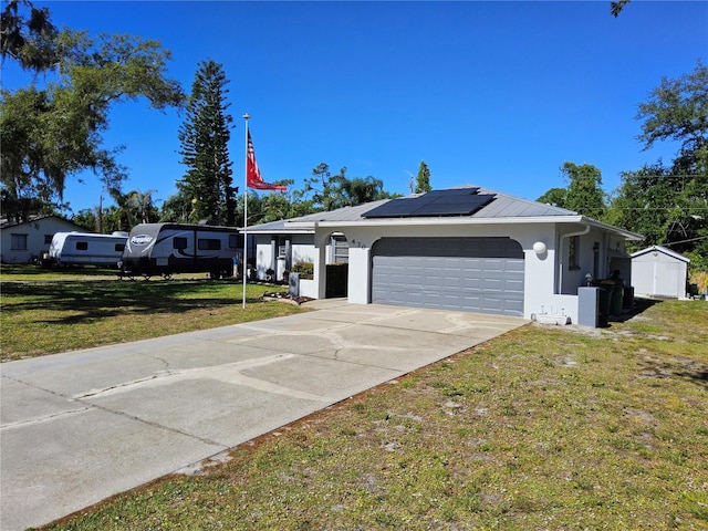 ranch-style home with solar panels, a storage unit, a garage, and a front lawn