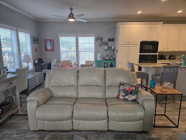 living room featuring dark hardwood / wood-style floors, ceiling fan, and ornamental molding