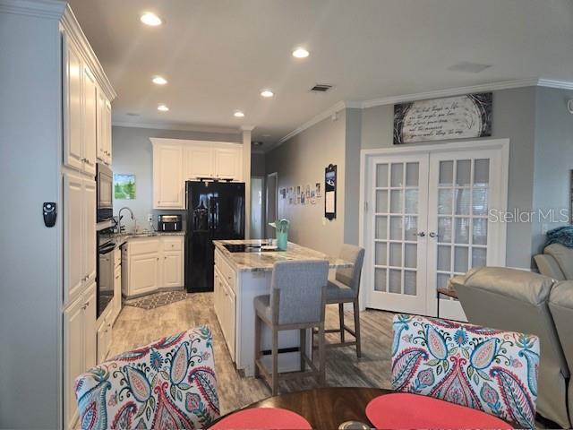 kitchen with french doors, a center island, white cabinetry, and black appliances