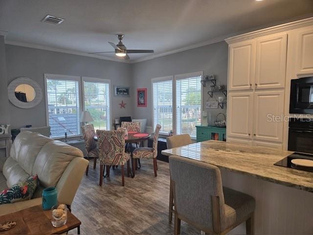 dining space with ceiling fan, wood-type flooring, and crown molding