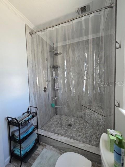 bathroom featuring toilet, curtained shower, and ornamental molding