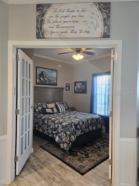 bedroom featuring ceiling fan, wood-type flooring, ornamental molding, and french doors