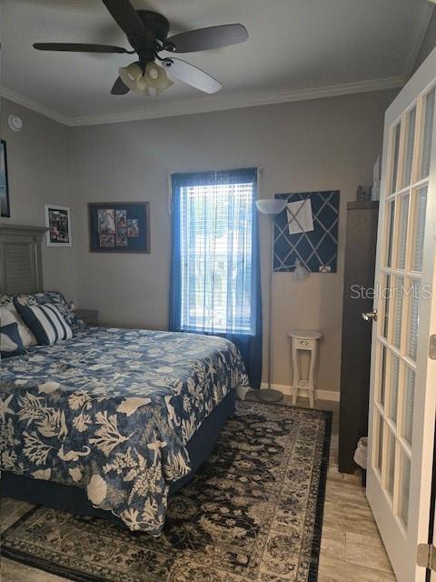 bedroom with light wood-type flooring, ceiling fan, and ornamental molding