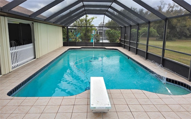 view of swimming pool with glass enclosure, a diving board, and a patio