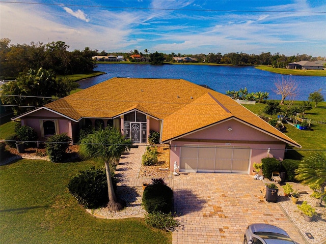 view of front facade featuring a water view, a garage, and a front lawn