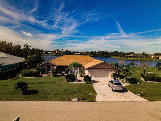 single story home featuring a front lawn, a water view, and a garage