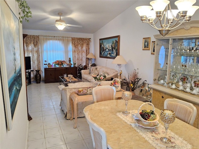 dining room with ceiling fan with notable chandelier, light tile patterned floors, and vaulted ceiling