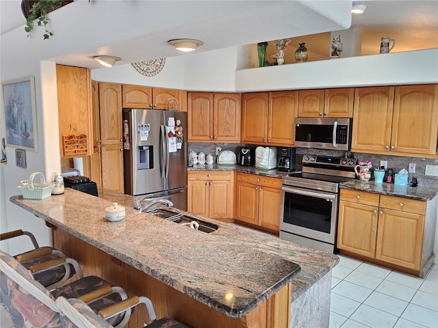 kitchen with a breakfast bar area, sink, appliances with stainless steel finishes, and tasteful backsplash