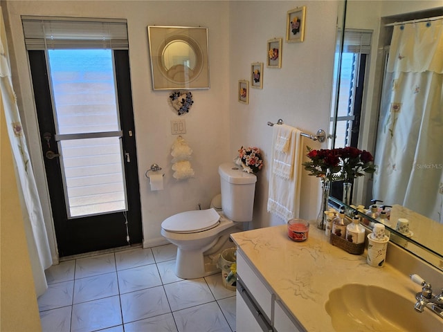 bathroom with tile patterned floors, plenty of natural light, vanity, and toilet