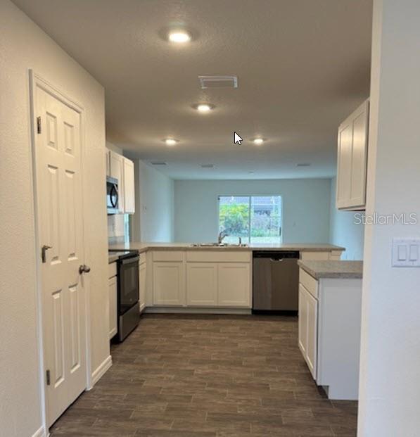 kitchen featuring white cabinetry, kitchen peninsula, and appliances with stainless steel finishes