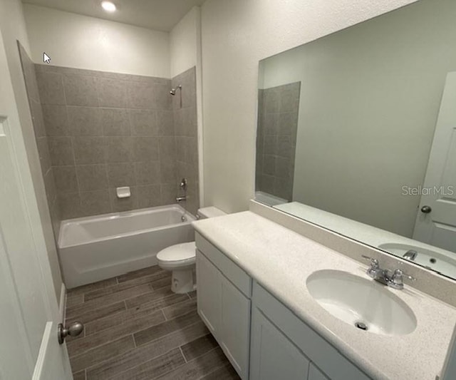 full bathroom featuring toilet, tiled shower / bath, and vanity