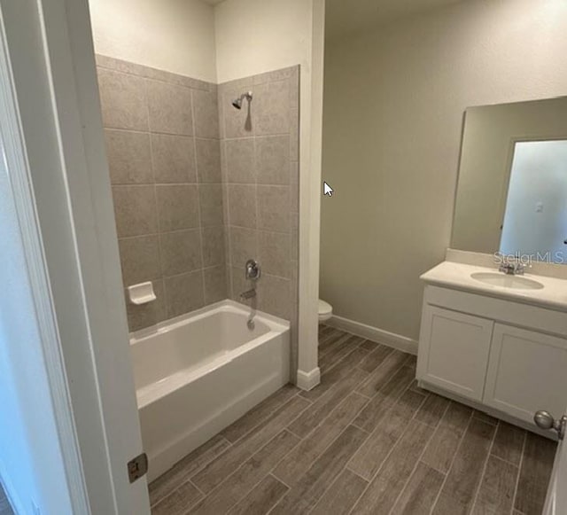 full bathroom featuring tiled shower / bath combo, vanity, and toilet