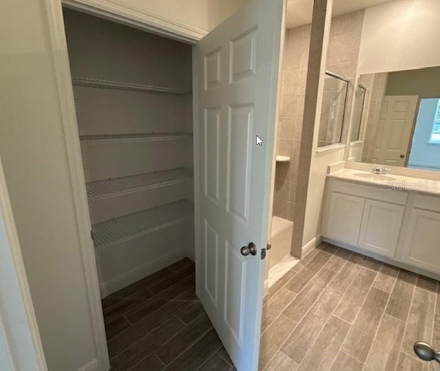 bathroom with walk in shower, vanity, and hardwood / wood-style flooring