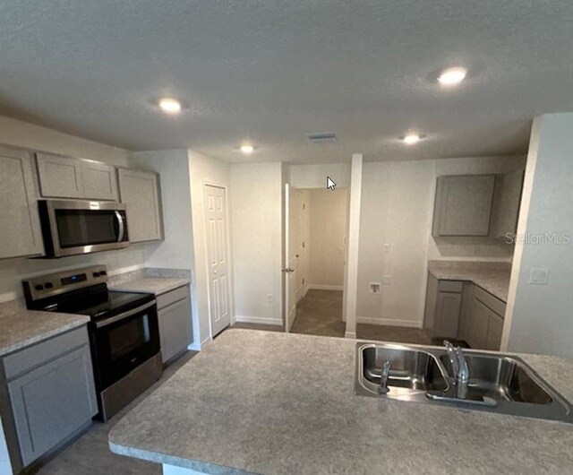 kitchen with appliances with stainless steel finishes, sink, and gray cabinetry