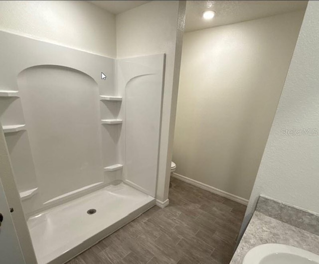 bathroom featuring toilet, hardwood / wood-style floors, vanity, and walk in shower