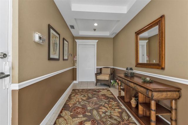 corridor featuring a raised ceiling and light tile patterned floors