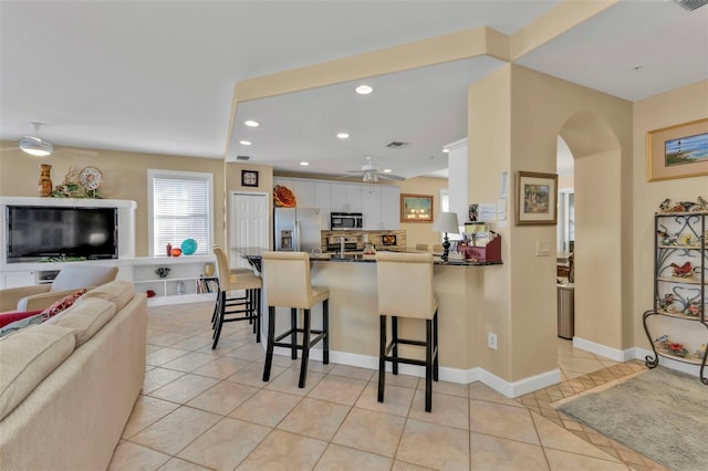 kitchen with white cabinets, ceiling fan, appliances with stainless steel finishes, kitchen peninsula, and a breakfast bar area