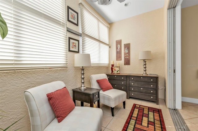 living area with ceiling fan and light tile patterned floors