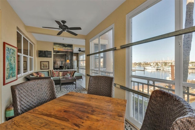 sunroom / solarium with ceiling fan and a water view