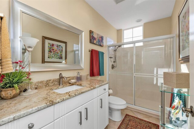 bathroom featuring tile patterned flooring, vanity, an enclosed shower, and toilet