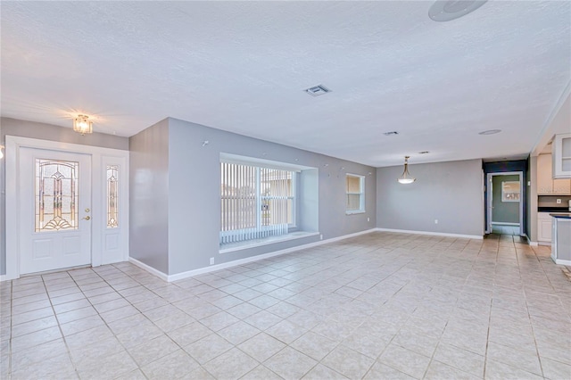 entryway with light tile patterned floors and a textured ceiling