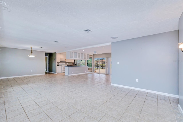 unfurnished living room with ceiling fan, light tile patterned floors, and a textured ceiling