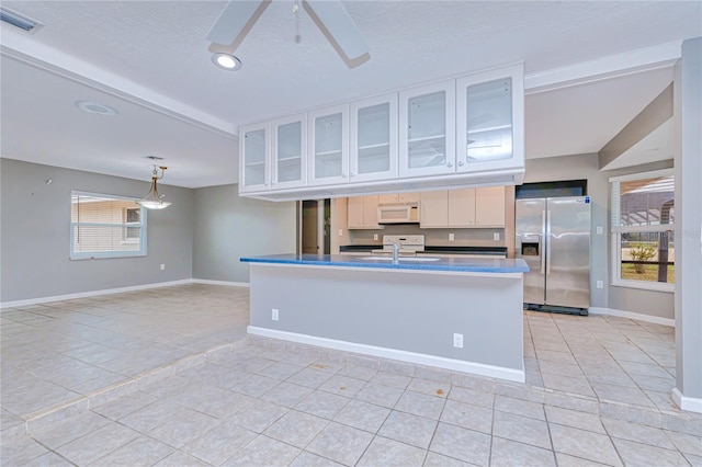 kitchen featuring sink, hanging light fixtures, ceiling fan, stainless steel fridge, and white cabinetry