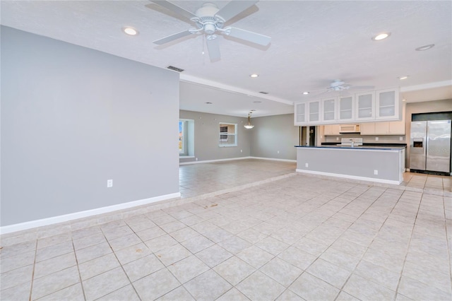 unfurnished living room featuring a textured ceiling, ceiling fan, and light tile patterned flooring